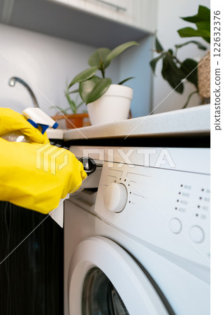 Housekeeper cleans kitchen appliances, ensuring regular maintenance to prevent limescale buildup and keep the washing machine running efficiently. Housekeeper cleans kitchen appliances, ensuring regular maintenance to prevent limescale buildup and keep the washing machine running efficiently. 122632376