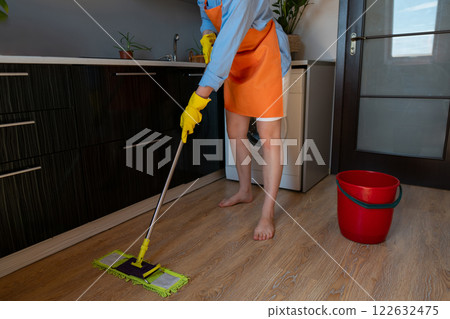 A woman cleans floors at home using eco-friendly products. Wet cleaning removes dust, pollen, and allergens effectively. A woman cleans floors at home using eco-friendly products. Wet cleaning removes dust, pollen, and allergens effectively. 122632475