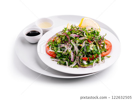Fresh mixed salad served on a white plate with dressing choices and lemon wedge 122632505