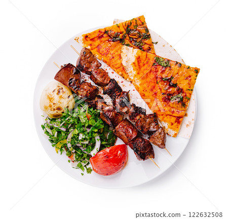 Delicious grilled skewers served with flatbread and fresh vegetables in a vibrant setting 122632508