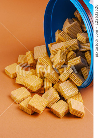 Crispy wafers scattered from an opened blue container on a brown surface Crispy wafers scattered from an opened blue container on a brown surface 122632526