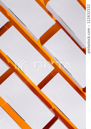 Colorful arrangement of blank packaging boxes on an orange background in a well-lit workspace Colorful arrangement of blank packaging boxes on an orange background in a well-lit workspace 122632552
