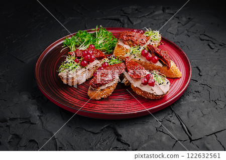 Savory bread slices topped with sun-dried tomatoes, sprouts, and red currants served on a vibrant plate 122632561