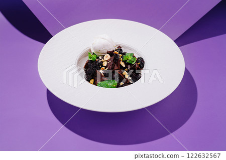 Gourmet dessert served in a modern bowl with distinctive purple backdrop during a culinary presentation Gourmet dessert served in a modern bowl with distinctive purple backdrop during a culinary presentation 122632567