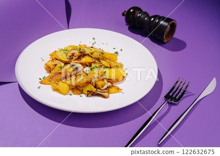 Delicious gourmet dish featuring sauteed potatoes and mushrooms served on a vibrant purple background 122632675