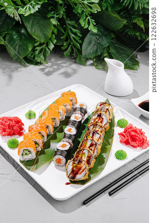 Delicious sushi platter featuring various rolls and garnishes served on a white plate 122632698