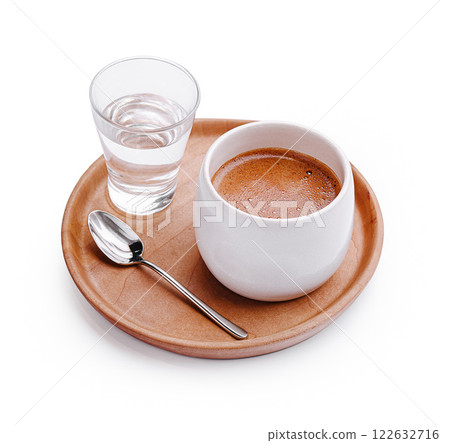 Hot beverage served with a glass of water on a wooden tray in a cozy setting 122632716