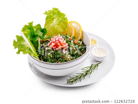 Fresh tabbouleh salad made with parsley, tomatoes, and lemon served in a stylish bowl on a white plate 122632728