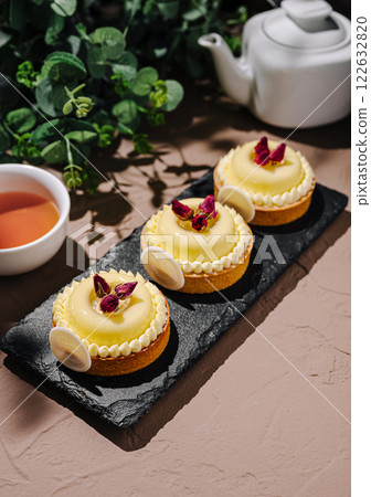 Delightful lemon tarts garnished with rose petals served with herbal tea in a cozy setting 122632820