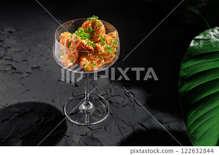 Fresh shrimp cocktail served elegantly in a crystal glass with green garnish on a dark textured surface 122632844