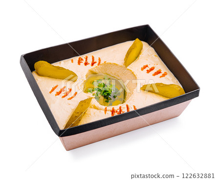 Homemade hummus served in a decorative container with pickles and garnish for a flavorful appetizer or snack 122632881