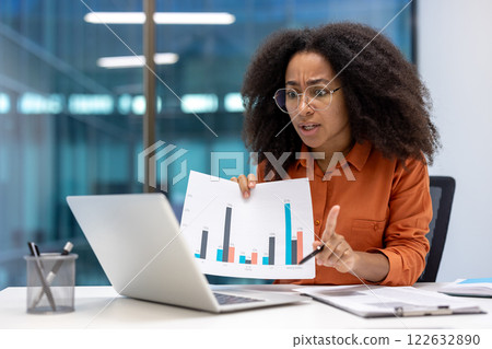 African American businesswoman in modern office analyzing bar chart on laptop. Professional showcasing data insights and engaging in business strategy meeting. African American businesswoman in modern office analyzing bar chart on laptop. Professional showcasing data insights and engaging in business strategy meeting. 122632890