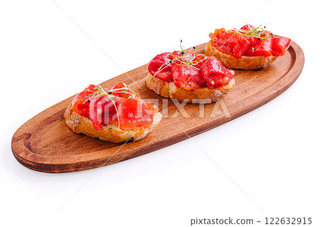 Deliciously crafted tapas served on a wooden platter with vibrant toppings at a modern culinary venue 122632915