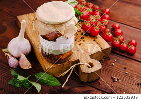Delicious homemade preserves with garlic, tomatoes, and basil arranged on a rustic wooden board 122632939