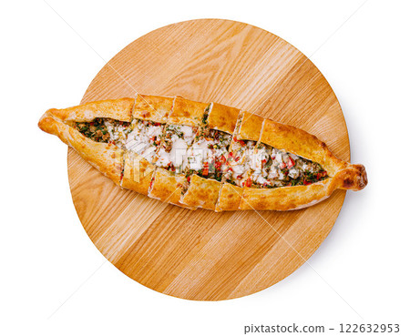 Traditional Turkish pide with filling served on a wooden platter in a cozy restaurant setting Traditional Turkish pide with filling served on a wooden platter in a cozy restaurant setting 122632953