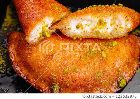 Crispy and sweet traditional dessert filled with creamy goodness and topped with crushed pistachios Crispy and sweet traditional dessert filled with creamy goodness and topped with crushed pistachios 122632973