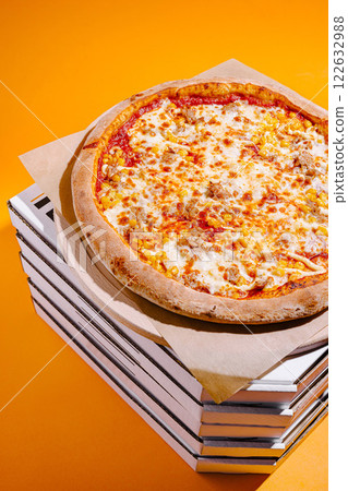 Pizza on top of stacked boxes with an orange background showcasing its delicious toppings Pizza on top of stacked boxes with an orange background showcasing its delicious toppings 122632988
