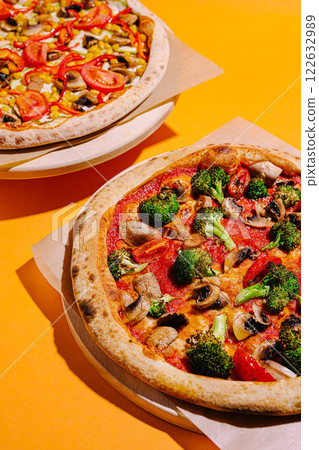Freshly baked vegetable pizzas on golden orange background with vibrant toppings waiting to be enjoyed Freshly baked vegetable pizzas on golden orange background with vibrant toppings waiting to be enjoyed 122632989