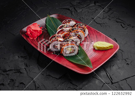 Sushi platter featuring assorted rolls garnished with wasabi and pickled ginger on a vibrant red plate Sushi platter featuring assorted rolls garnished with wasabi and pickled ginger on a vibrant red plate 122632992