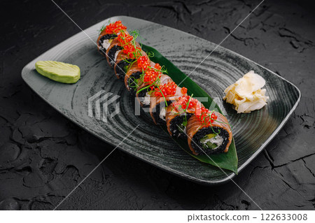 Delicious sushi platter presented elegantly on a textured black plate with fresh ingredients and toppings Delicious sushi platter presented elegantly on a textured black plate with fresh ingredients and toppings 122633008