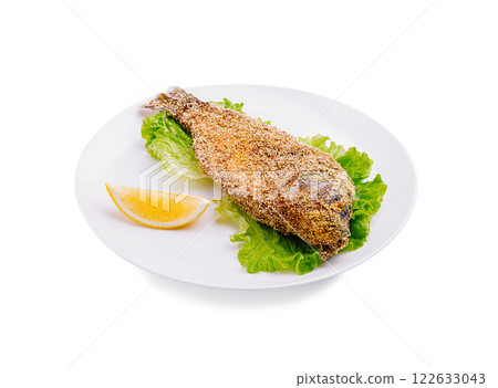 Crispy fried fish served on a white plate with lettuce and lemon wedge Crispy fried fish served on a white plate with lettuce and lemon wedge 122633043