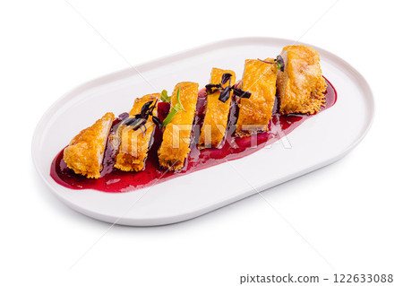 Gourmet dessert featuring sliced pastries drizzled with berry sauce on a white plate 122633088