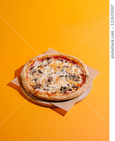 Freshly made pizza with a golden crust on an orange background ready to be enjoyed Freshly made pizza with a golden crust on an orange background ready to be enjoyed 122633097