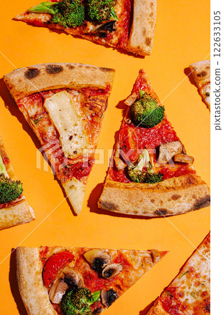 Colorful assortment of pizza slices with vegetables arranged on a vibrant orange background Colorful assortment of pizza slices with vegetables arranged on a vibrant orange background 122633105