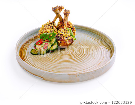 Deliciously plated chicken drumsticks with crunchy coating and refreshing cucumber salad on a rustic dish Deliciously plated chicken drumsticks with crunchy coating and refreshing cucumber salad on a rustic dish 122633129