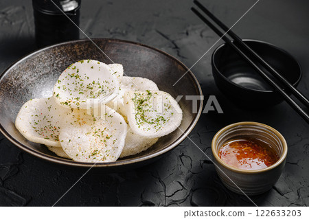 Crispy snack served with dipping sauce in a stylish bowl on a textured surface Crispy snack served with dipping sauce in a stylish bowl on a textured surface 122633203