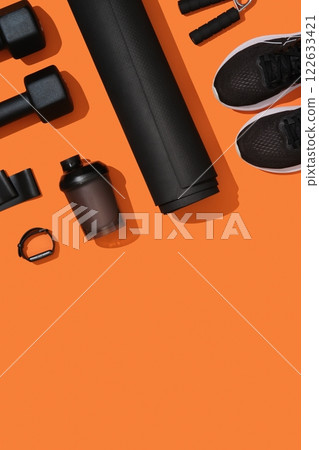 Vertical banner with black workout equipment, dumbbells, mat, sneakers, bottle, hand grip on orange background. Fitness, sports items, healthy lifestyle concept. Space for your text Vertical banner with black workout equipment, dumbbells, mat, sneakers, bottle, hand grip on orange background. Fitness, sports items, healthy lifestyle concept. Space for your text 122633421