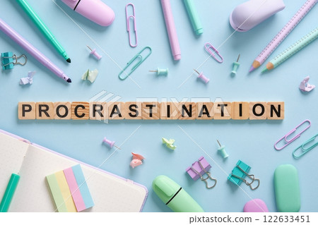 The word Procrastination in English laid out in wooden cubes on a background of office supplies 122633451