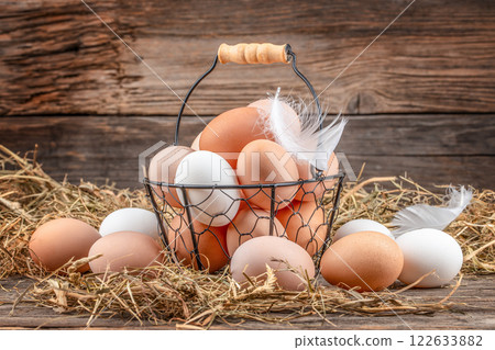 farmer collects eggs at eco poultry farm, free range chicken farm. basket of eggs on a wooden background farmer collects eggs at eco poultry farm, free range chicken farm. basket of eggs on a wooden background 122633882