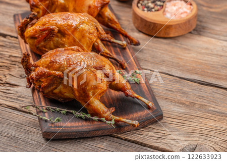 Baked quail on a wooden board, top view. copy space 122633923