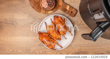 roasted quails with from the hot air fryer oven on a wooden background. top view. copy space roasted quails with from the hot air fryer oven on a wooden background. top view. copy space 122633929