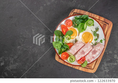 plate with fried eggs, ham and salad. Keto breakfast. Brunch top view. copy space for text plate with fried eggs, ham and salad. Keto breakfast. Brunch top view. copy space for text 122633970