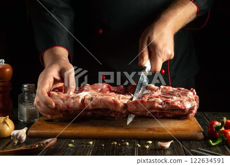 A skilled chef expertly carves a large cut of meat on a wooden board surrounded by fresh herbs and spices. The atmosphere is warm and inviting, showcasing a culinary passion for crafting meals A skilled chef expertly carves a large cut of meat on a wooden board surrounded by fresh herbs and spices. The atmosphere is warm and inviting, showcasing a culinary passion for crafting meals 122634591