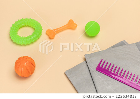 Pet supplies and playful items including a training pad, a comb, toy balls, a rubber ring and a chew bone for dogs. 122634812