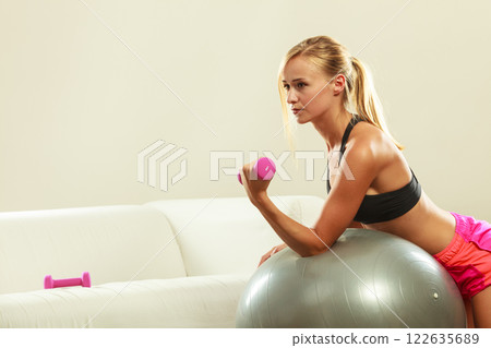 Woman with gym ball and dumbbell doing exercise 122635689