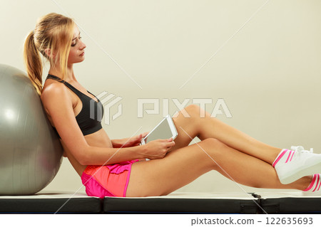 Fit woman sitting on floor with tablet pc Fit woman sitting on floor with tablet pc 122635693