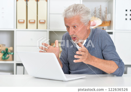 Portrait of senior man with laptop at home 122636526