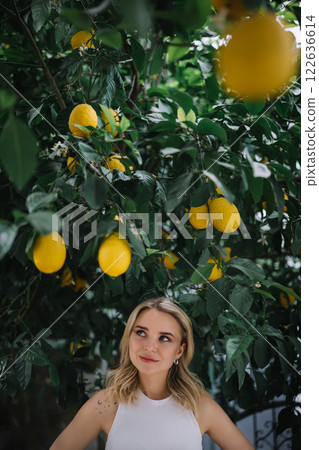 Outdoor portrait of beautiful young woman posing near lemon tree 122636614