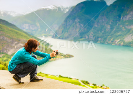 Female tourist taking photo at norwegian fjord Female tourist taking photo at norwegian fjord 122636737