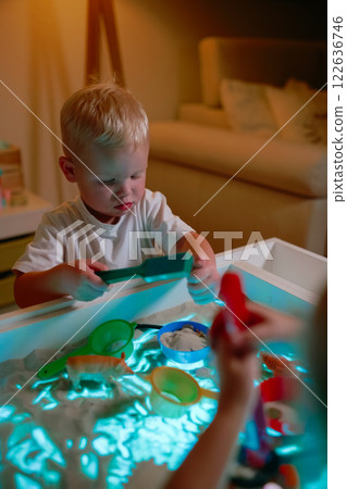 Preschoolers playing on sensory box. Preschoolers playing on sensory box. 122636746