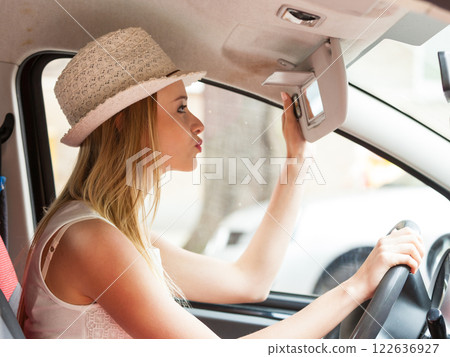 Distracted woman driving her car looking in mirror Distracted woman driving her car looking in mirror 122636927