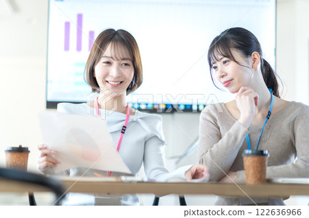 A young businesswoman having a meeting while holding documents 122636966