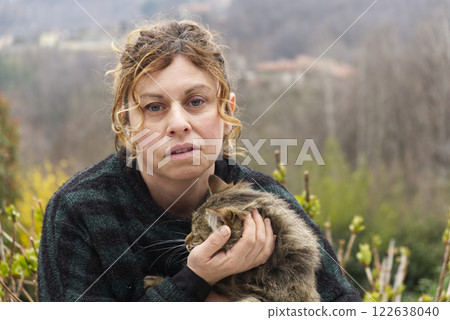 brunette fifty aged caucasian woman with green striped mallet cuddles a cat brunette fifty aged caucasian woman with green striped mallet cuddles a cat 122638040