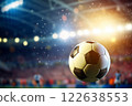 A soccer ball is in the air, surrounded by players on a field 122638553