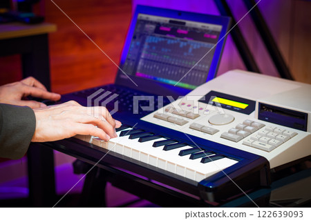 male professional music producer, composer, arranger hands playing on midi keyboard keys with music sequencer in home studio. music production male professional music producer, composer, arranger hands playing on midi keyboard keys with music sequencer in home studio. music production 122639093