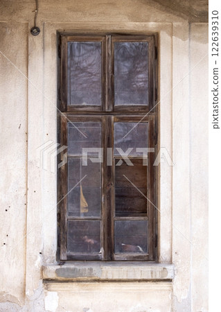 Old wooden window with broken glass on the wall of an abandoned house Old wooden window with broken glass on the wall of an abandoned house 122639310